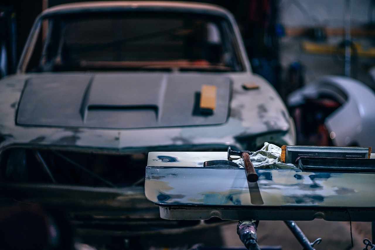 Classic automobile restoration project inside a repair garage with body panels and tools in the foreground, representing Financing a mechanic shop startup, truck repair shop financing, auto repair shop startup loans, tire inventory financing, and automotive lift financing for entrepreneurs building, expanding, and equipping modern automotive service businesses.
