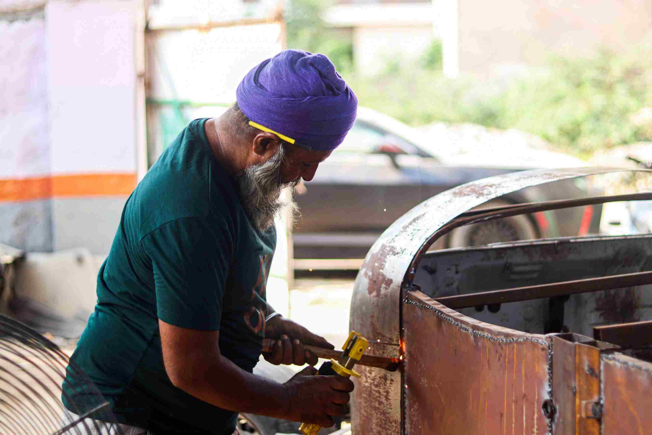 Automotive fabrication specialist performing custom metalwork and restoration on a vehicle body panel inside a repair facility, representing Auto repair shop startup loans, repair garage funding, auto repair capital providers, repair shop funding marketplace, and automotive CRM financing for automotive businesses seeking growth capital, technology investments, facility expansion, and equipment funding.
