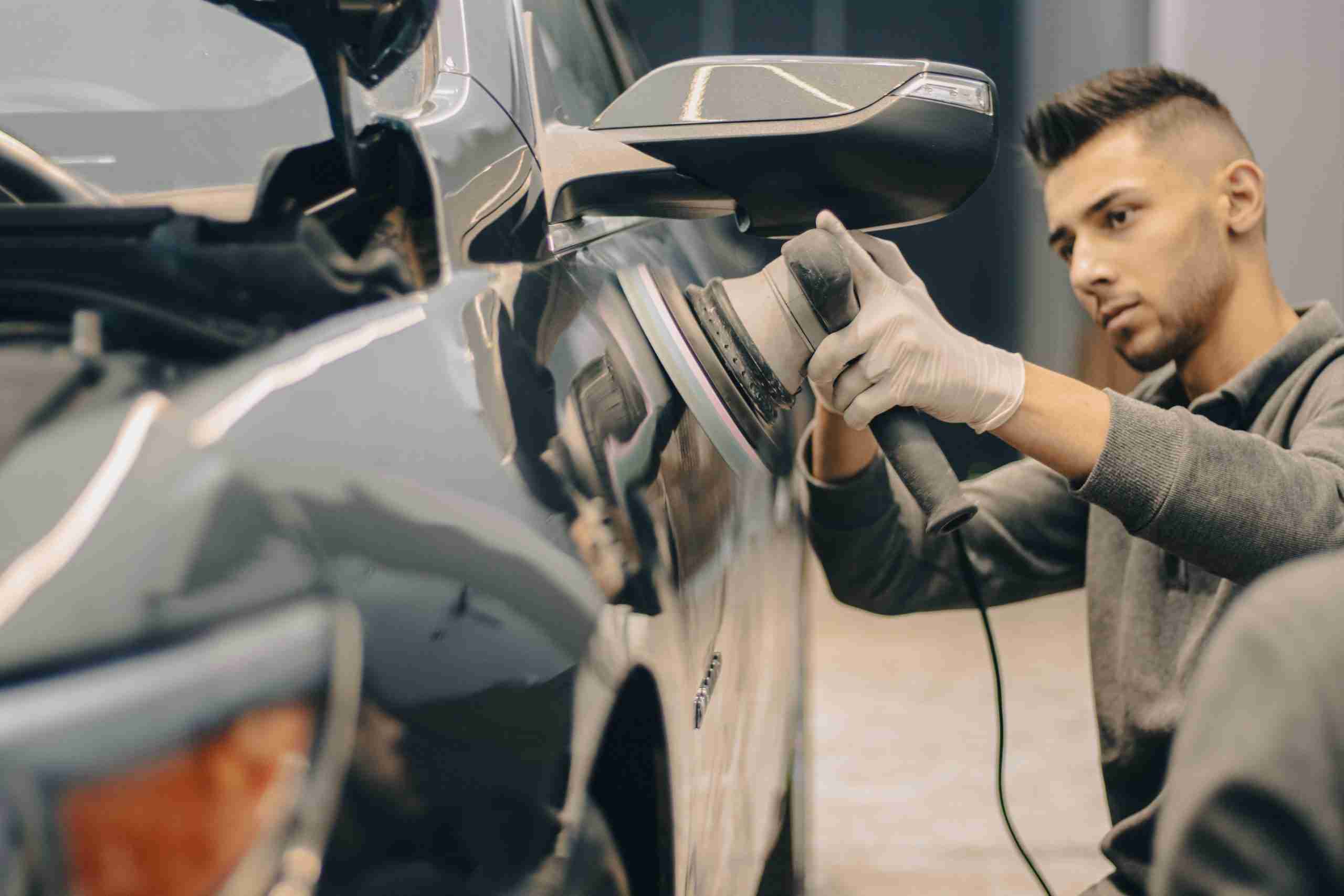 Automotive technician polishing and repairing a vehicle body panel inside a professional repair facility, representing Mechanic shop purchase loans, diagnostic machine financing, wheel inventory financing, automotive finance programs, and alignment rack financing used by repair shops to acquire businesses, purchase equipment, maintain inventory, and expand automotive service operations.