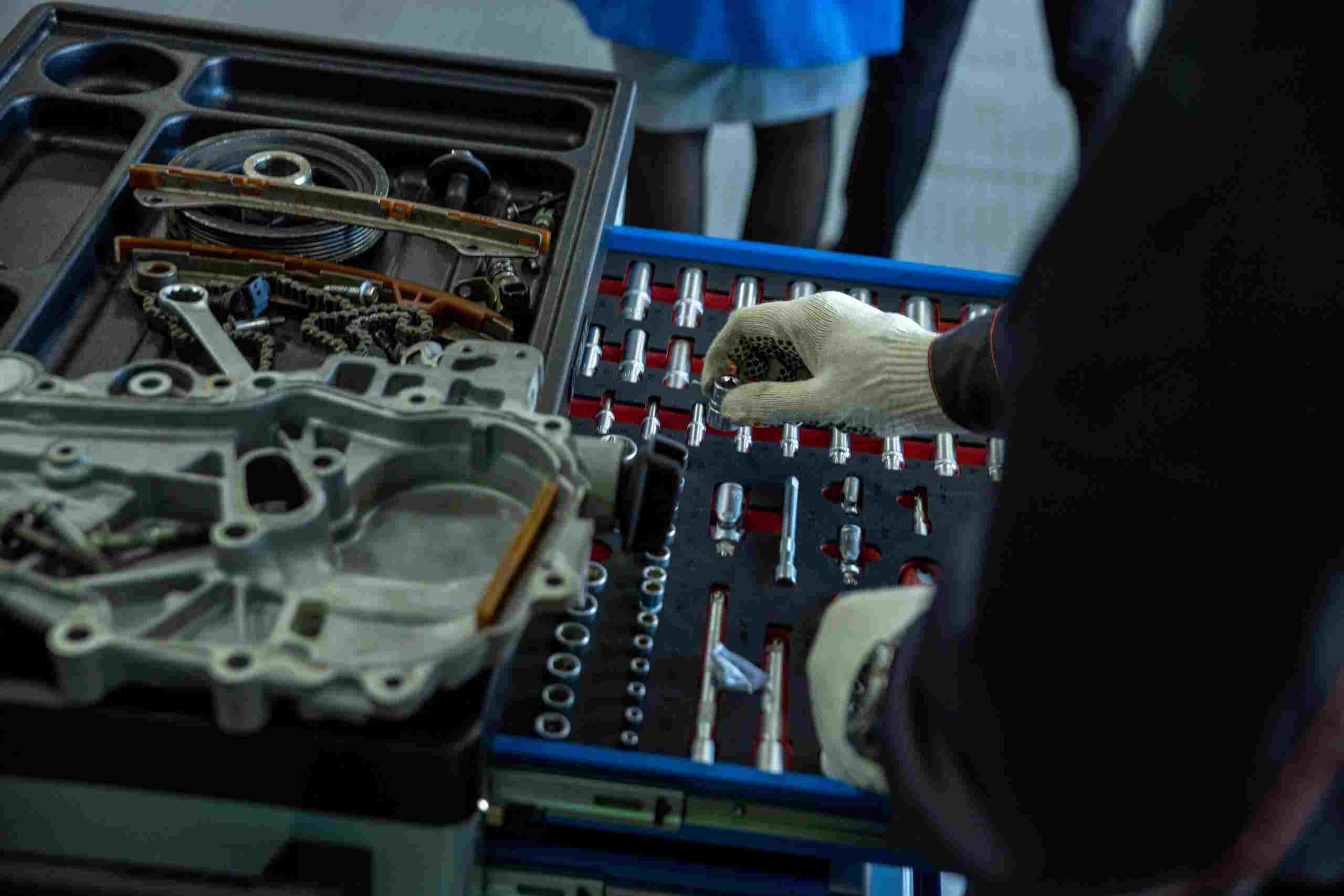 Automotive technician organizing drivetrain components and repair tools during a transmission service, representing tire equipment loans, vehicle painting equipment financing, tire shop expansion funding, mechanic business financing, and drivetrain repair financing for automotive shops investing in equipment, facility growth, and specialized repair services.