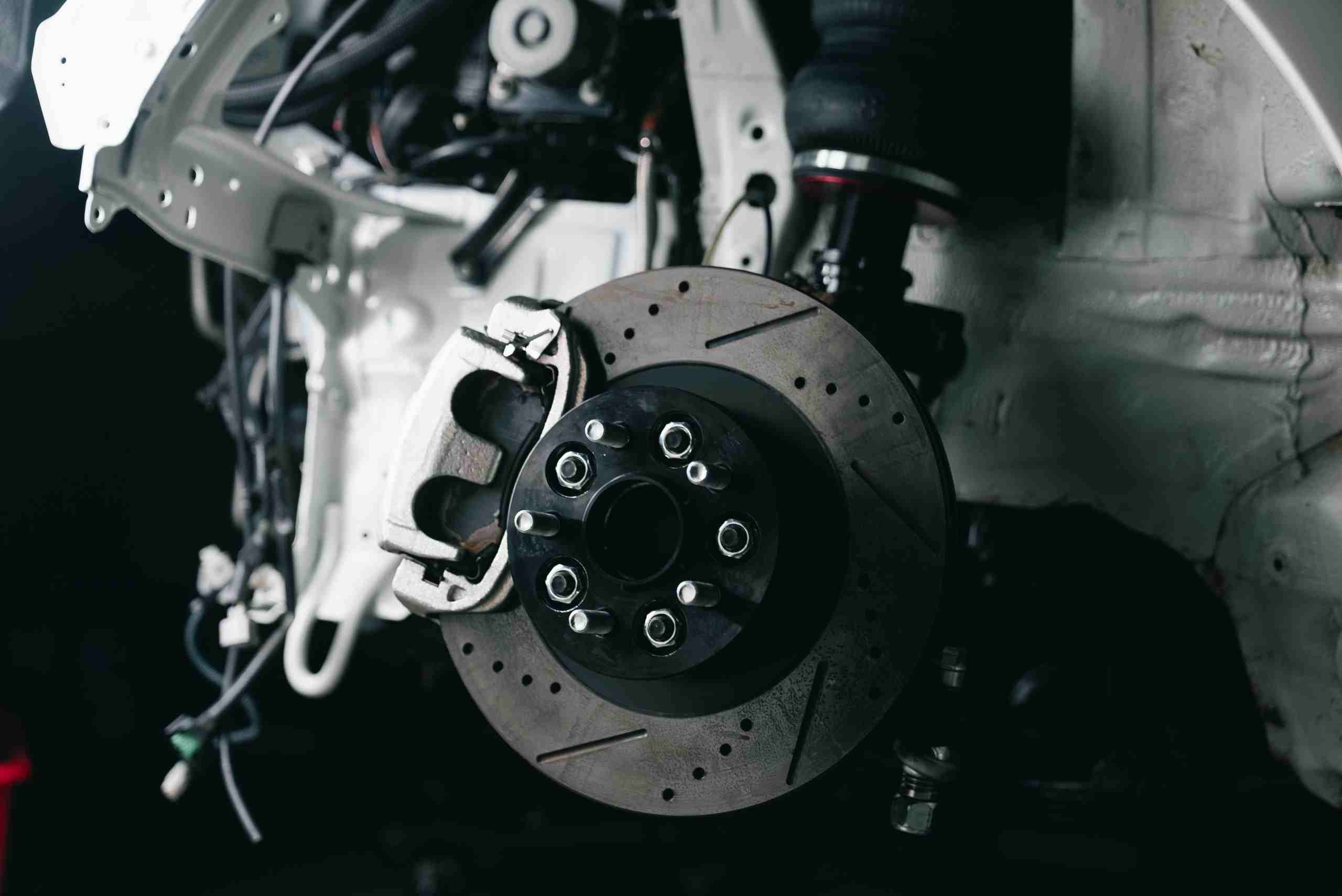 Close-up of a high-performance vehicle brake rotor and suspension assembly inside a professional automotive repair facility, representing automotive inventory funding, diesel repair shop financing, automotive property financing, fleet maintenance financing, and fleet operations financing for growing repair shops, fleet service centers, and commercial vehicle maintenance businesses.