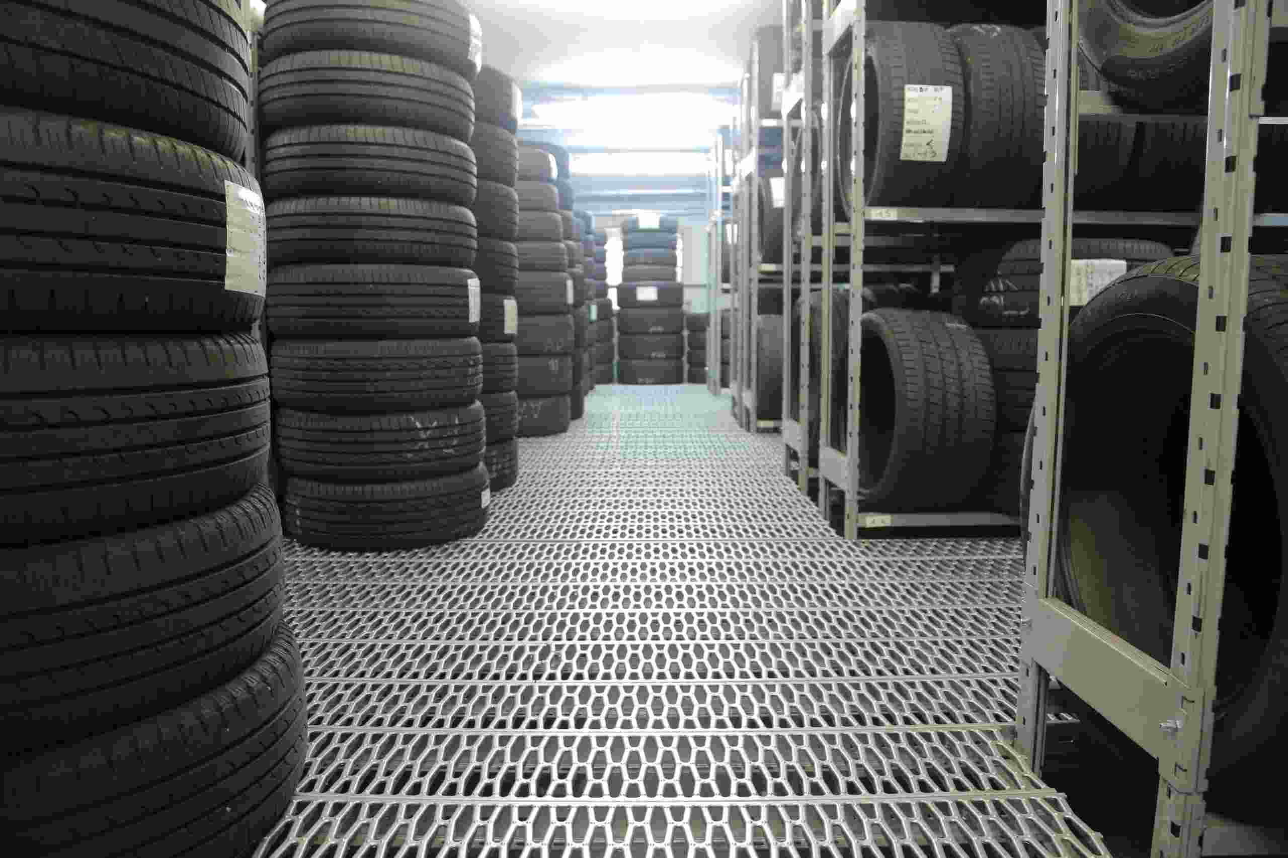 Large tire warehouse with rows of stacked tires and organized storage racks, representing Auto body equipment loans, vehicle inspection equipment financing, tire service center financing, tire machine financing, and tire inventory financing used to support equipment purchases, inventory management, and automotive business growth.