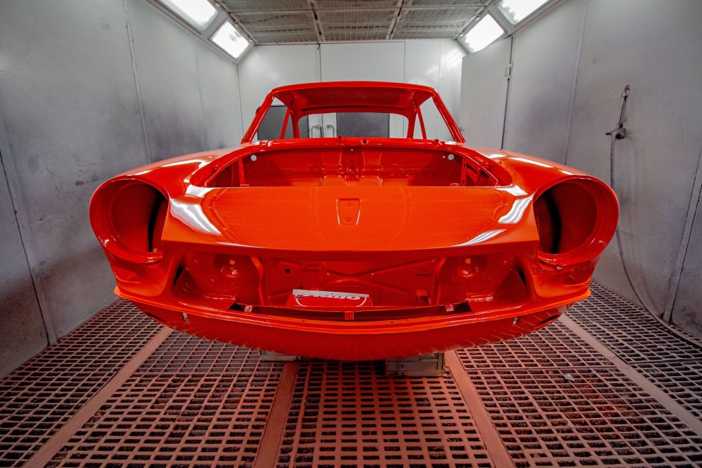 Freshly painted red vehicle body inside an automotive paint booth, representing Vehicle inspection software financing, EV repair shop financing, auto repair capital providers, diagnostic equipment financing, and tire inventory financing for modern automotive repair businesses.