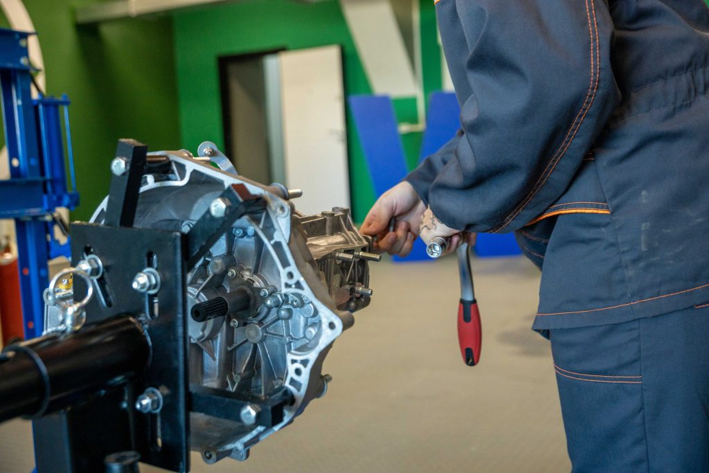 Mechanic working on an automotive transmission in a repair shop representing Automotive business expansion loans, heavy duty repair shop funding, auto shop real estate financing, apply for auto shop loans, and auto shop loans for automotive business growth.