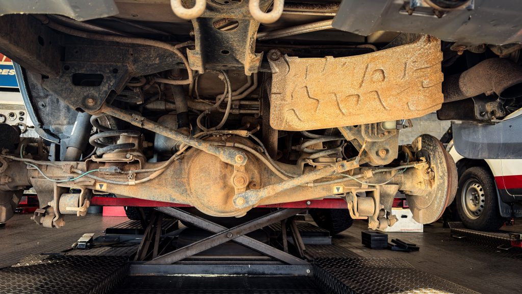 Vehicle undercarriage and suspension being serviced on an automotive lift, representing an Auto body shop loan, auto repair shop acquisition financing, tire inventory financing, collision repair equipment financing, and an auto paint shop loan for automotive businesses.