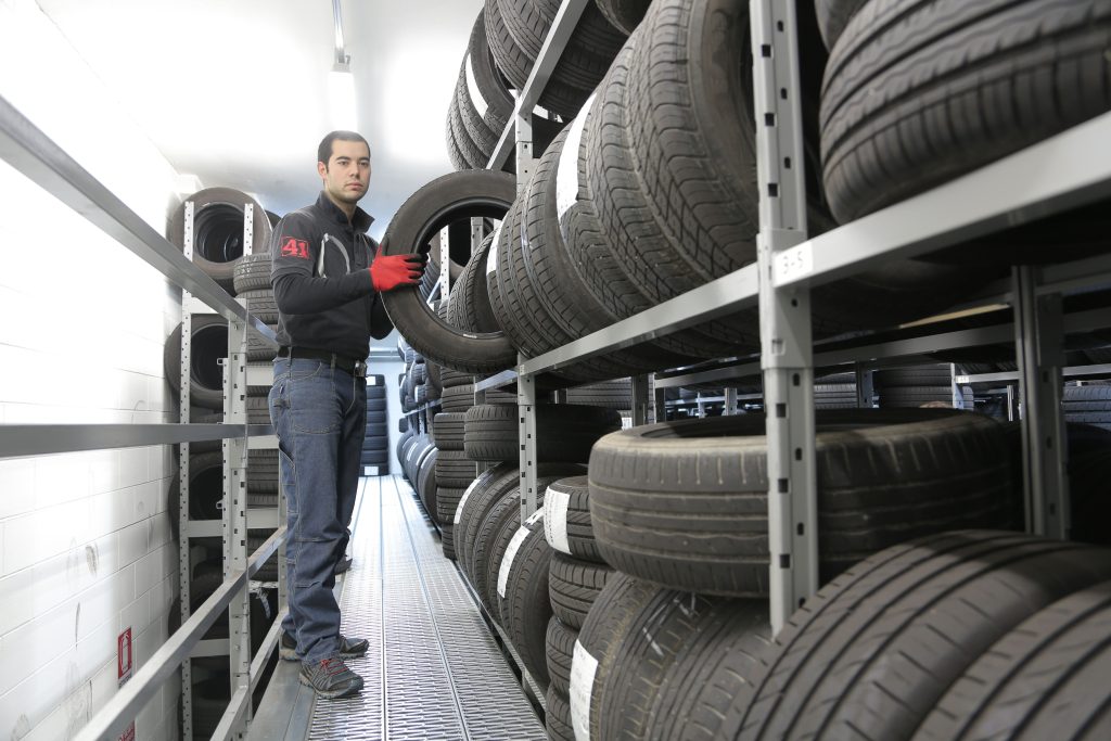 Automotive worker handling tires inside a tire storage facility, representing Mechanic business financing options, EV repair shop financing, financing a mechanic shop startup, tire shop loan, and auto repair shop expansion loans for automotive businesses.