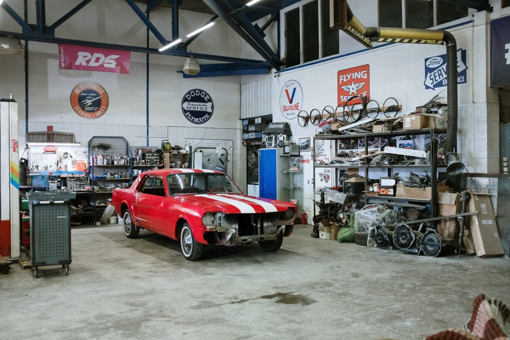 Classic red car undergoing restoration inside an automotive repair garage, representing Mechanic business acquisition funding, automotive entrepreneur financing, repair shop scaling capital, wheel balancer financing, and vehicle lift loans for automotive business owners.