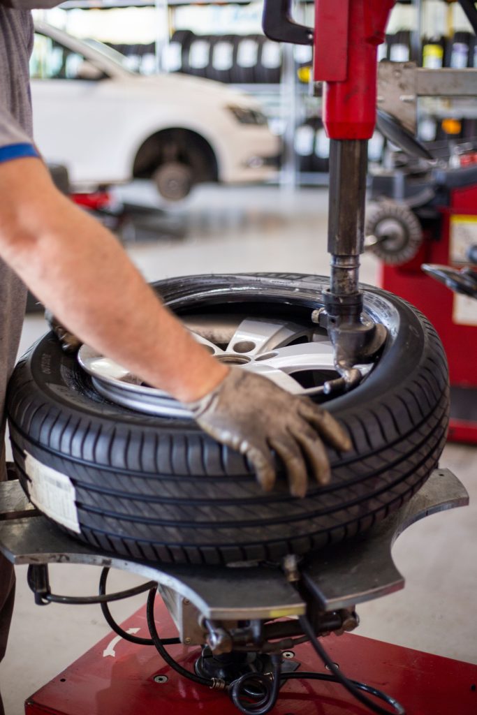 Mechanic changing a tire with automotive shop equipment representing Vehicle lift loans, shop compressor financing, automotive business acquisition funding, shop compressor financing, and performance shop financing for automotive businesses.