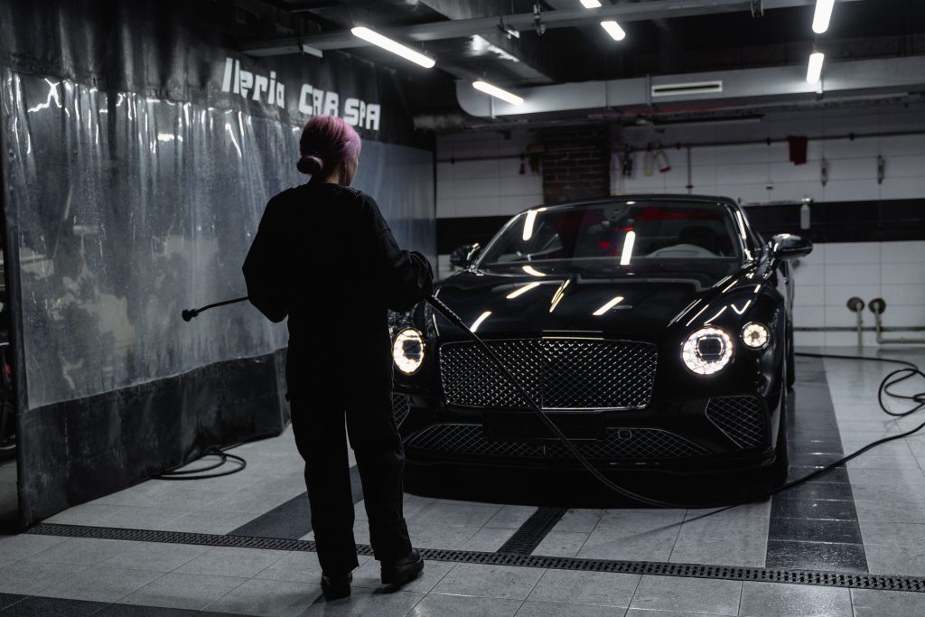 Automotive detailing professional cleaning a luxury vehicle inside a modern service facility, representing Automotive business financing, finance automotive repair equipment, finance an automotive paint booth, and diesel repair shop apply for financing for automotive businesses.