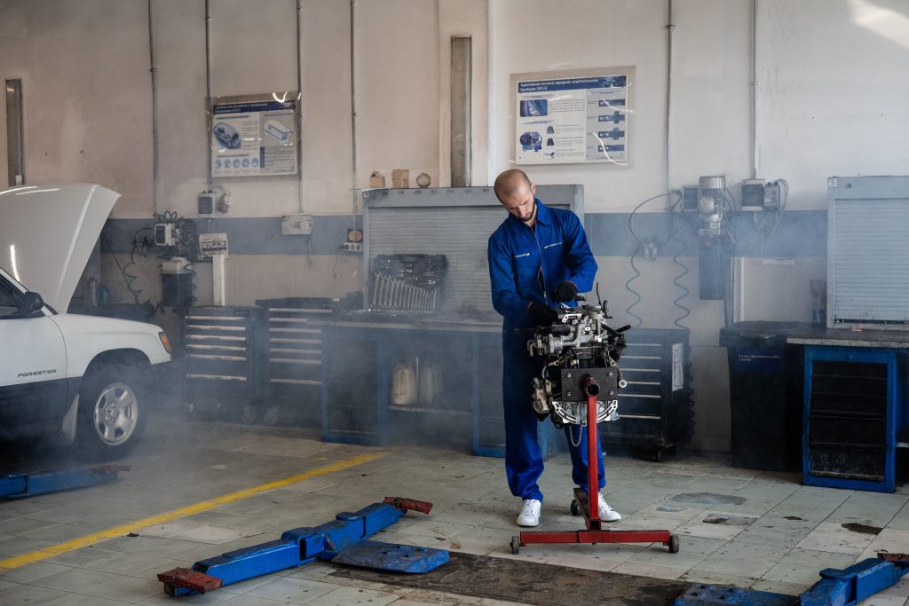 Mechanic working on an automotive engine inside a professional repair shop, representing Transmission shop financing, auto service center startup capital, garage acquisition financing, brake lathe financing, and repair facility growth capital for automotive business owners.
